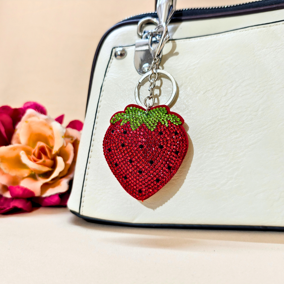 strawberry keychain on a white handbag in front of a beige background