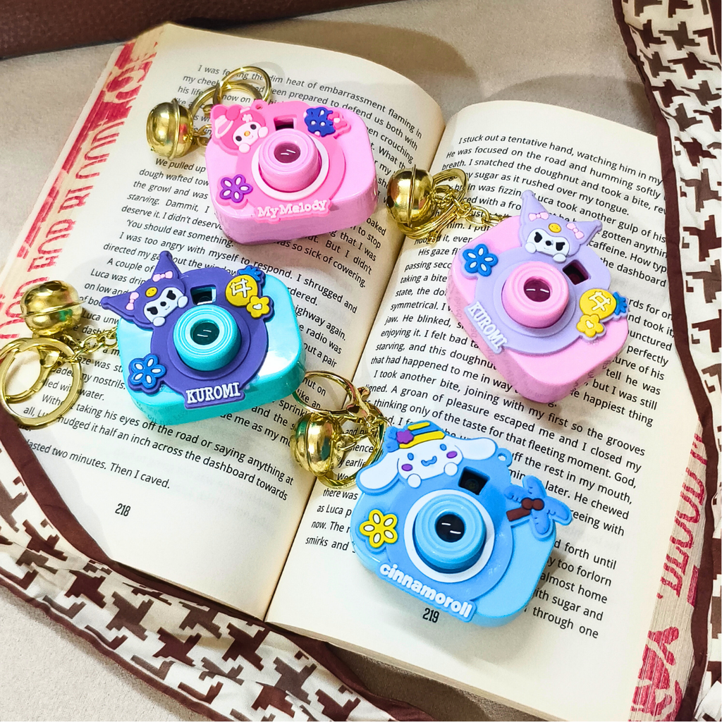 Four colorful camera-shaped charms on an open book