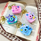 Four colorful camera-shaped charms on an open book