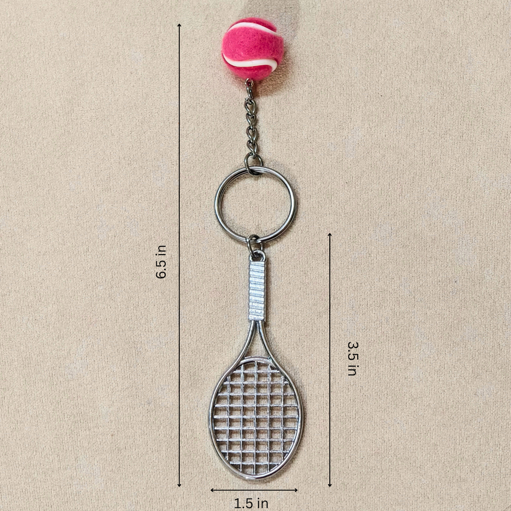A tennis racket-shaped keychain with a pink tennis ball charm, shown on a beige background with dimension lines indicating a height of 6.5 inches, width of 1.