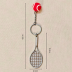 A tennis racket keychain with a red and white tennis ball charm, shown with dimension lines indicating a height of 6.5 inches, width of 1.
