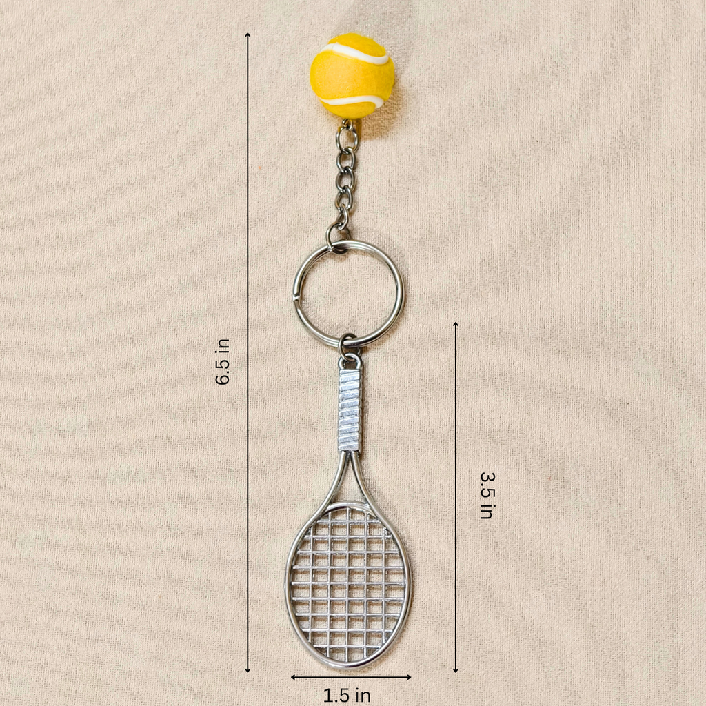 A tennis-themed keychain featuring a silver metal tennis racket and key ring, topped with a yellow tennis ball charm, shown on a beige background with dimension lines and text indicating measurements.