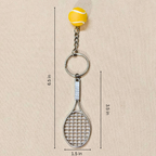 A tennis-themed keychain featuring a silver metal tennis racket and key ring, topped with a yellow tennis ball charm, shown on a beige background with dimension lines and text indicating measurements.