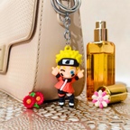 Keychain with anime character, flowers, and perfume bottle on a reflective surface