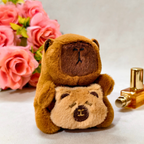 Two brown teddy bears sitting next to each other with pink roses and a gold perfume bottle in the background.