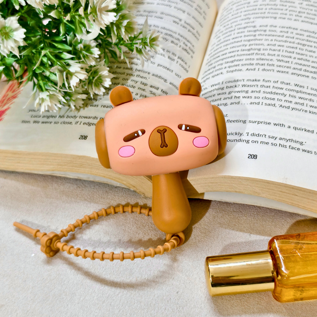 Cute animal-shaped perfume bottle on an open book with flowers and a bottle cap.