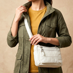 Person wearing a green jacket holding a white bag against a beige background
