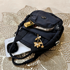 Black crossbody bag with gold accents on a textured surface