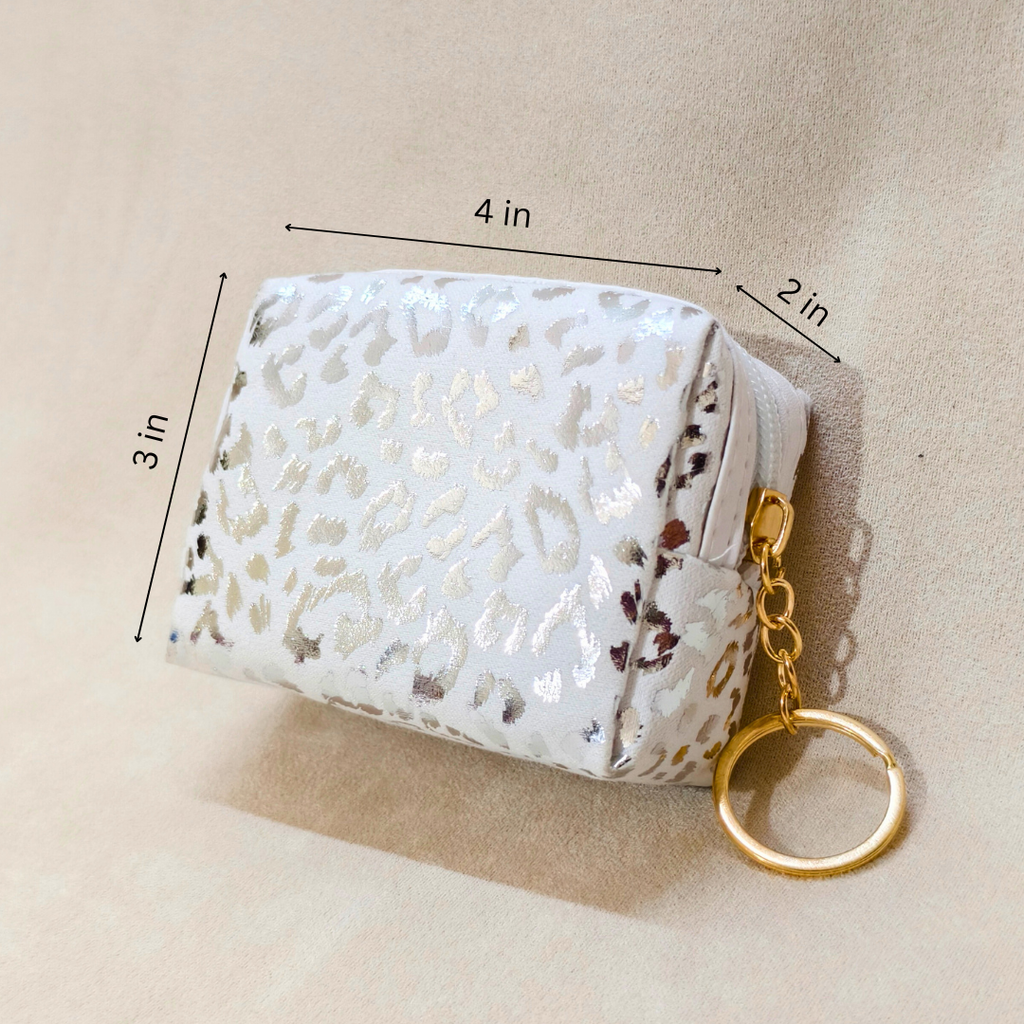 White leopard print pouch with gold keychain on beige background