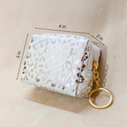 White leopard print pouch with gold keychain on beige background