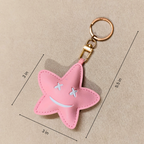 Pink star-shaped keychain with measurements on a beige background