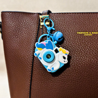 Unicorn camera-shaped keychain attached to a brown leather bag.
