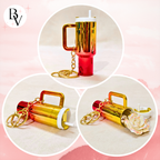 A collage showing a small cylindrical keychain bottle or lip balm container in metallic gold and red, with a white cap, straw, and gold keychain rings. Three circular views display different angles and a rose-shaped charm attached.