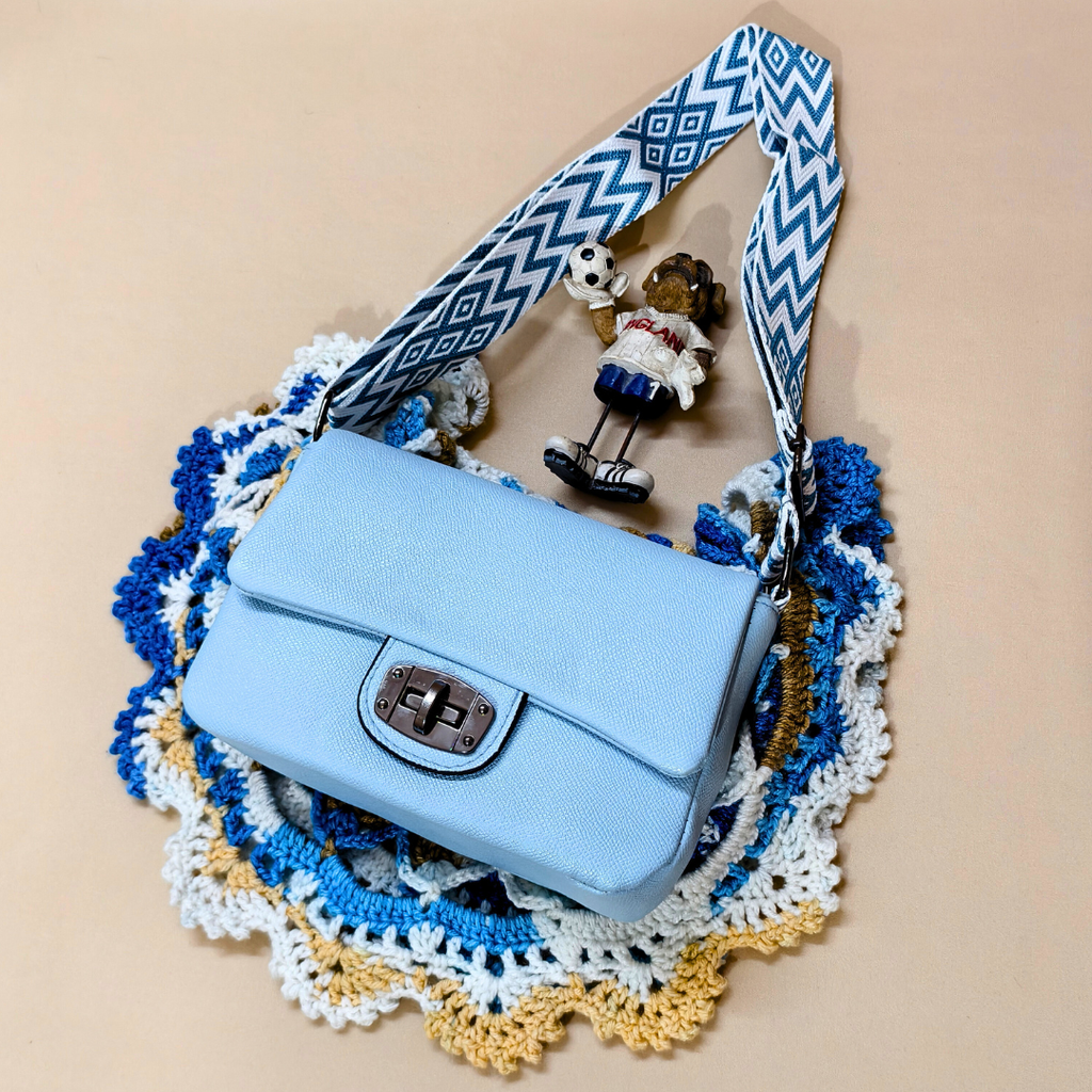 Blue handbag with a decorative strap on a beige background