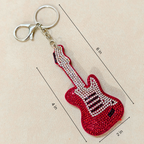 Red guitar-shaped keychain with rhinestones on a beige background with measurements.