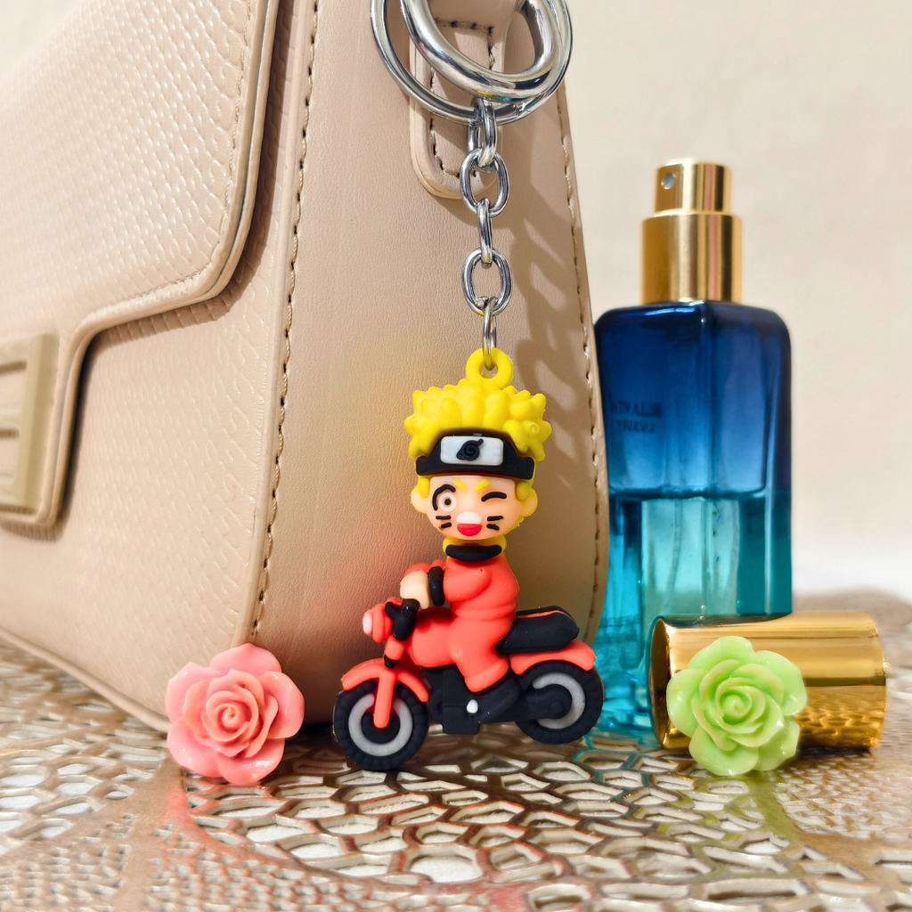 Keychain of a character on a motorcycle next to a blue perfume bottle and flowers.