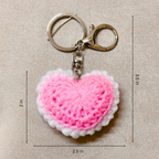 Pink heart-shaped keychain with measurements on a beige background