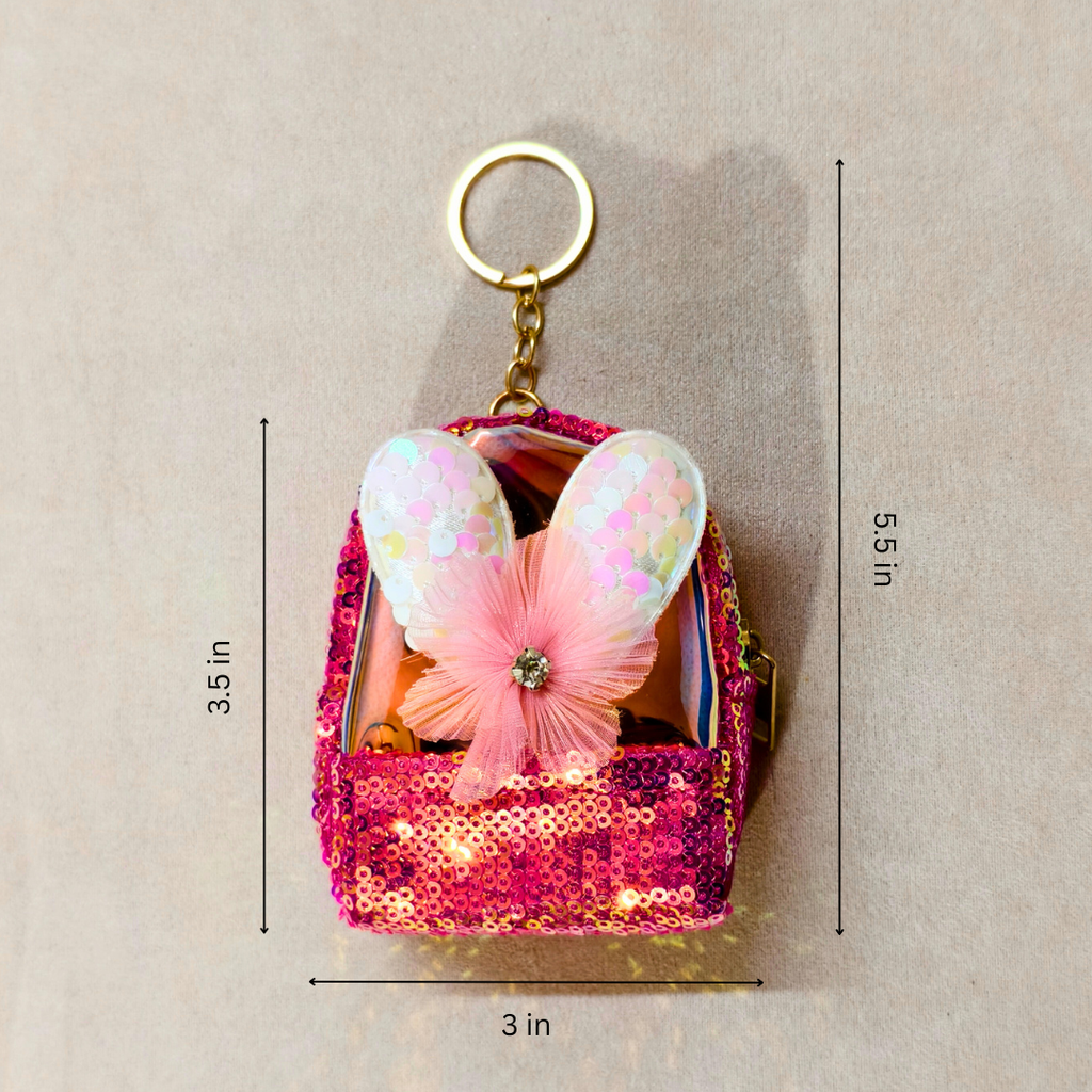 Pink sequin bag with butterfly wings keychain on a beige background