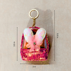 Pink sequin bag with butterfly wings keychain on a beige background