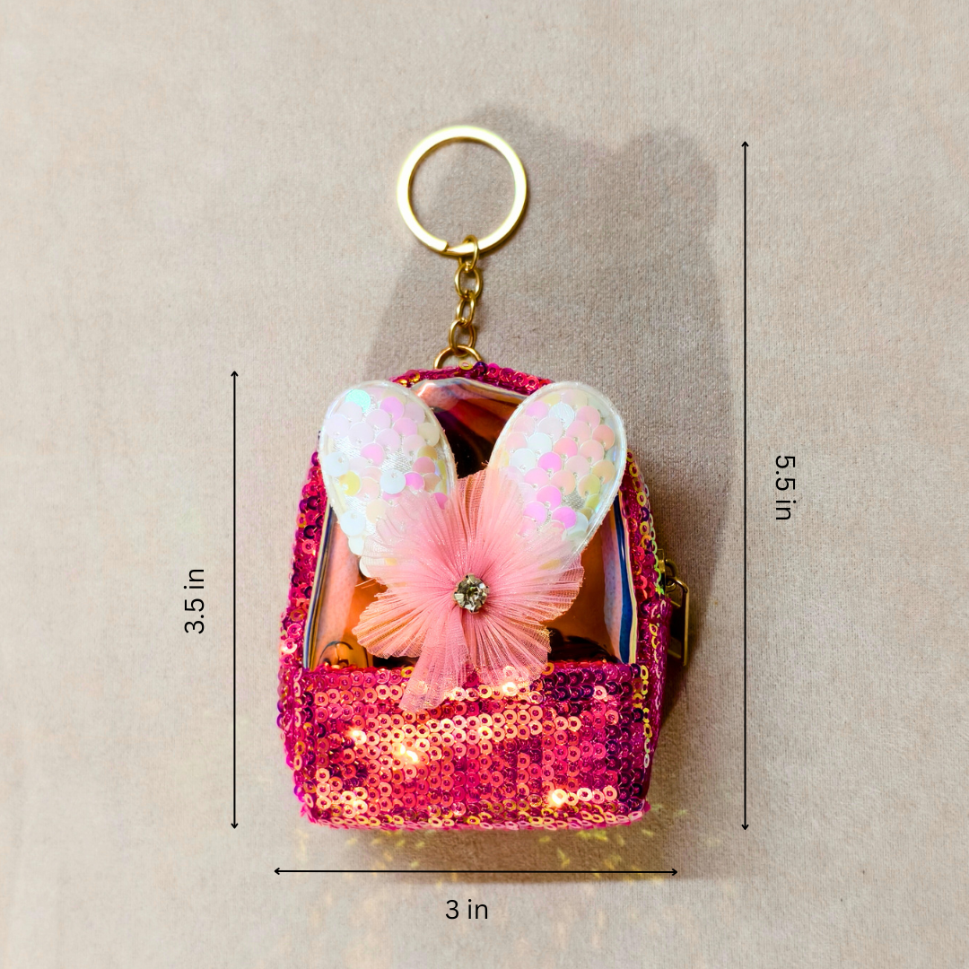 Pink sequin bag with butterfly wings keychain on a beige background
