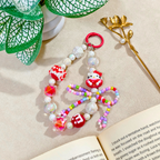 Colorful beaded keychain with a character charm on a beige surface with a book and decorative elements.
