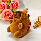 Plush toy bear with a pumpkin on a table with flowers and a bottle in the background
