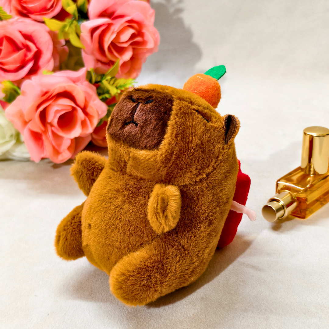 Plush toy bear with a pumpkin on a table with flowers and a bottle in the background