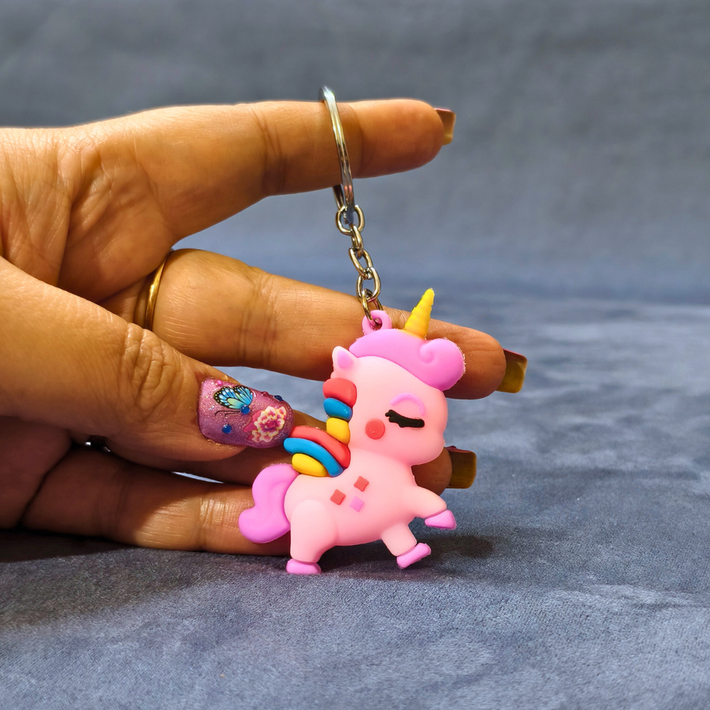 Pink unicorn keychain held by a hand on a gray background