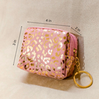 Pink pouch with gold leopard print and keychain on a beige background