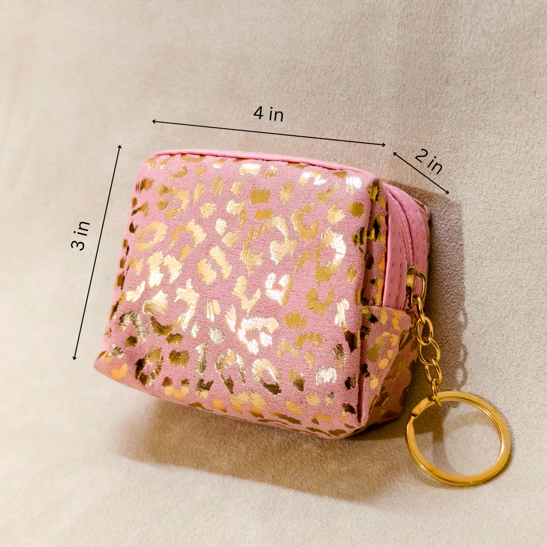 Pink pouch with gold leopard print and keychain on a beige background
