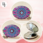 Three circular product views of a compact mirror with an oval face featuring a colorful mandala pattern and evil eye design, plus a silver metal hinge and mirror. The background is a soft pink gradient.