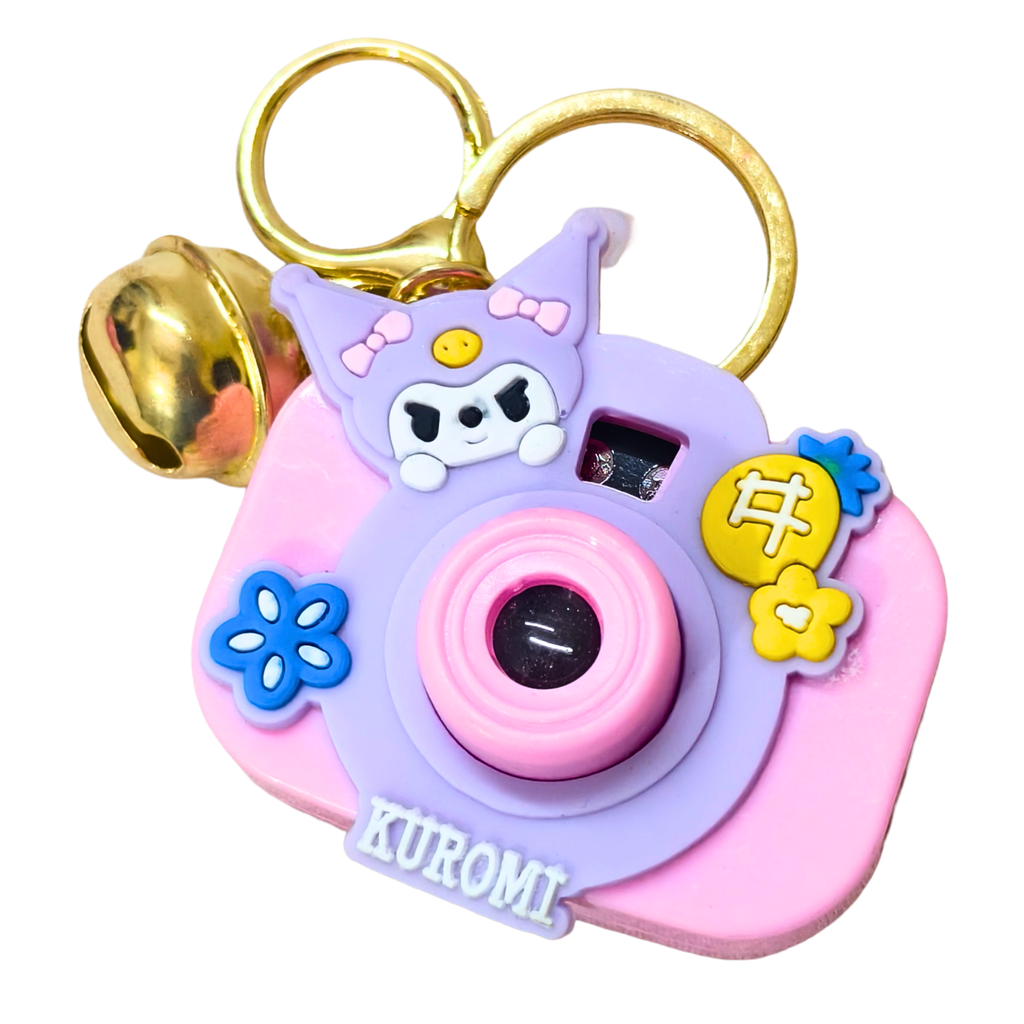 Pink and purple camera-shaped keychain with cartoon character and 'Kuromi' branding on a white background