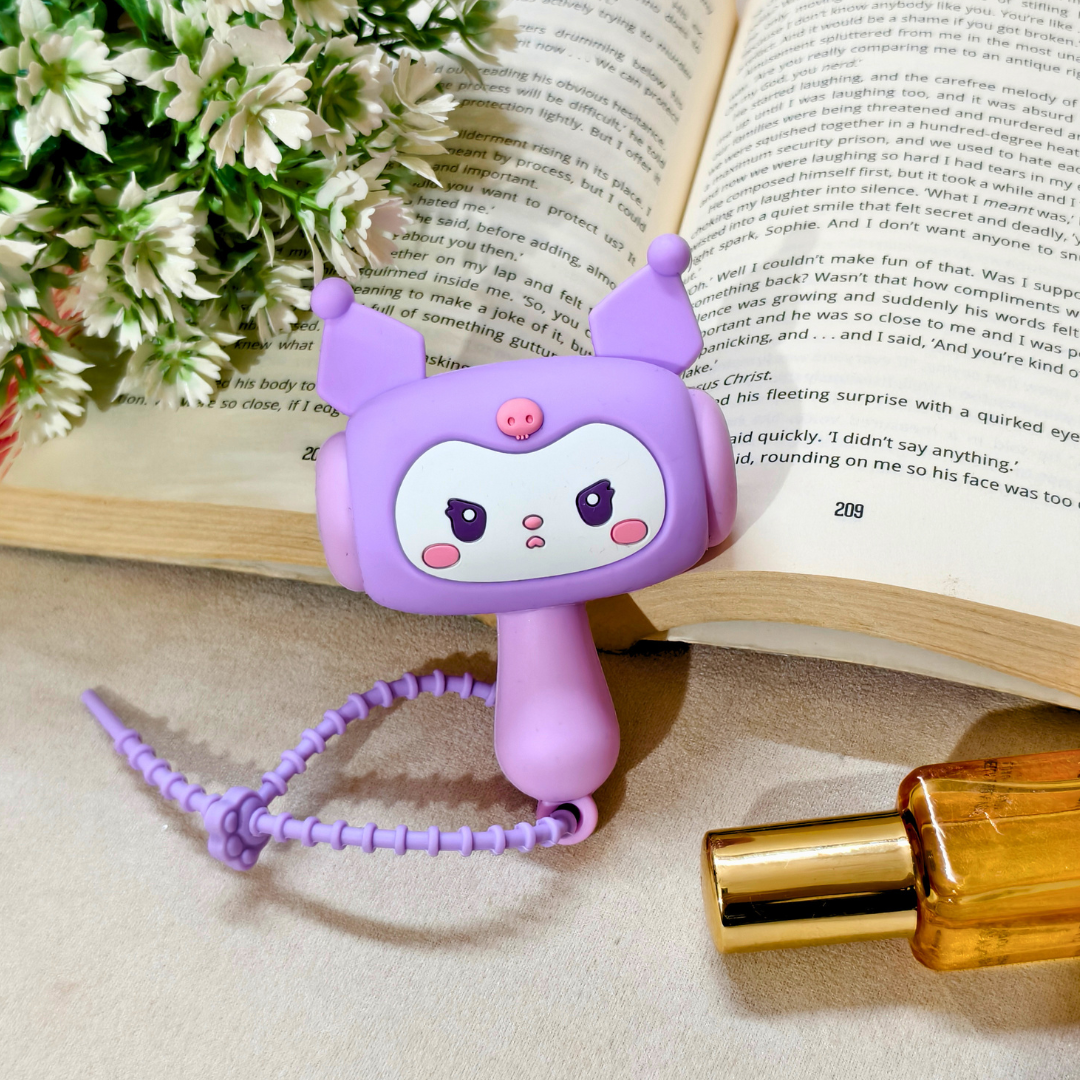 Purple cartoon character phone holder on a book with flowers and a perfume bottle in the background