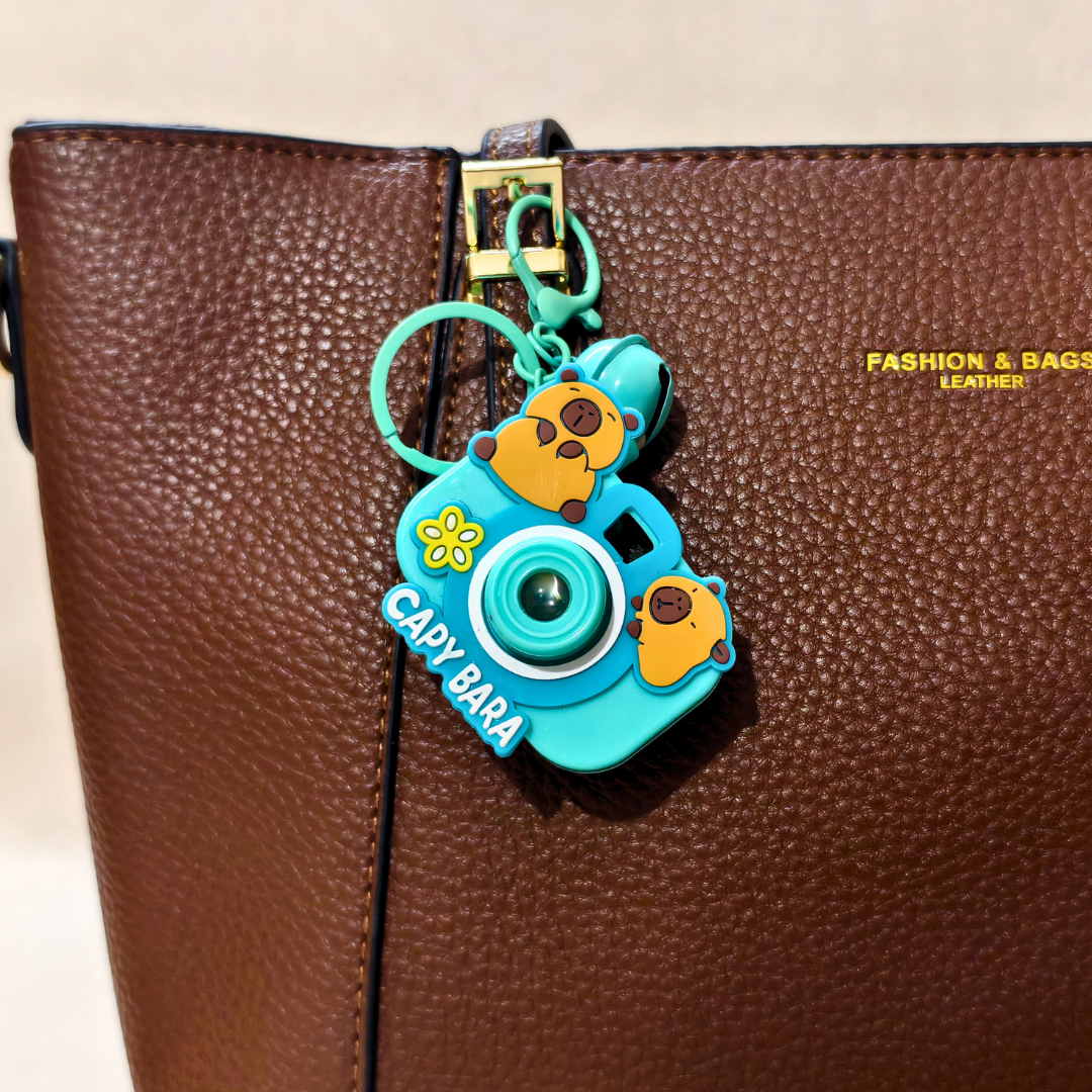 Capybara-themed camera charm on a brown leather bag with 'Fashion & Bags' branding.