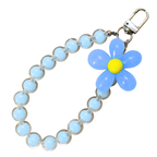 Blue Flower Phone Charm In Front Of White Background.