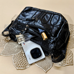 Black leather bag with a white electronic device on a decorative beige surface