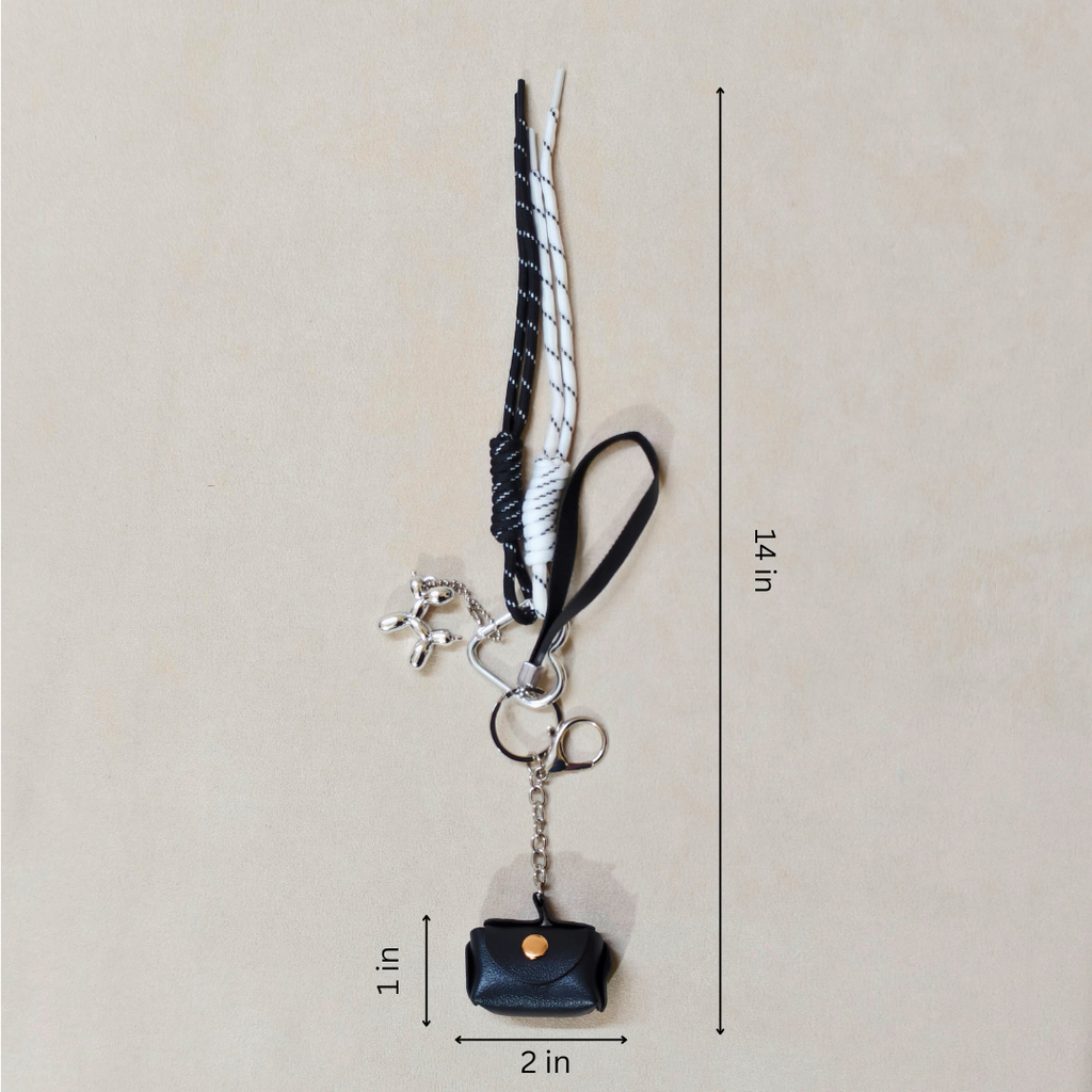 Black and white keychain with a small bag charm on a beige background, showing measurements.