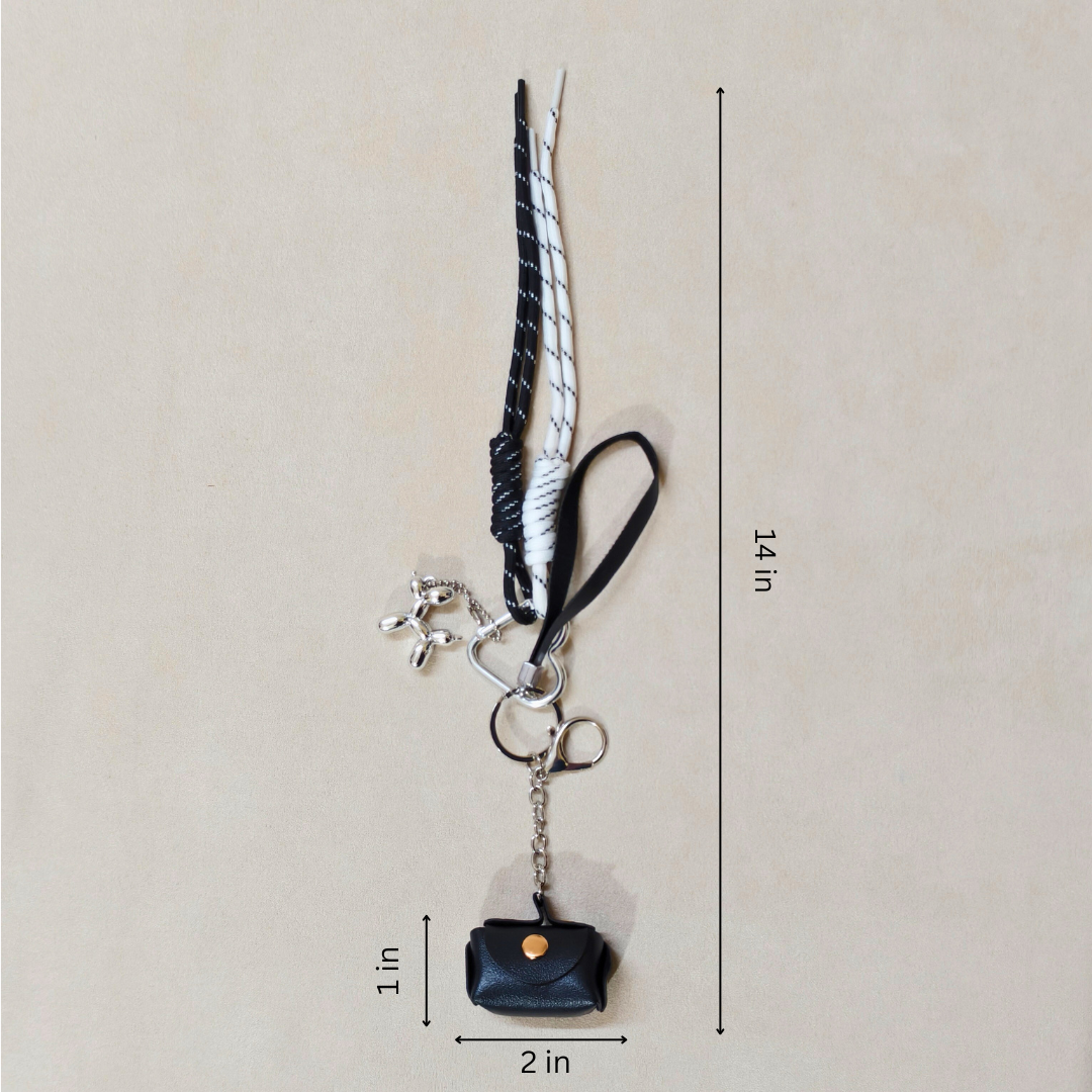 Black and white keychain with a small bag charm on a beige background, showing measurements.