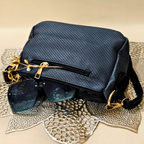 Blue textured handbag with sunglasses on a textured surface