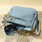 Blue textured handbag with sunglasses on a decorative surface