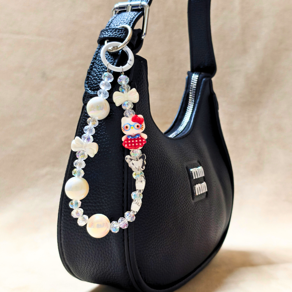 Black handbag with a decorative beaded strap on a beige background