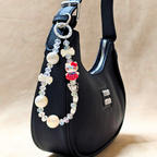 Black handbag with a decorative beaded strap on a beige background