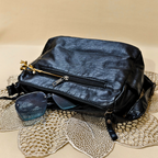 Black leather bag with sunglasses on a textured surface