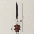 Brown teddy bear keychain with measurements on a beige background
