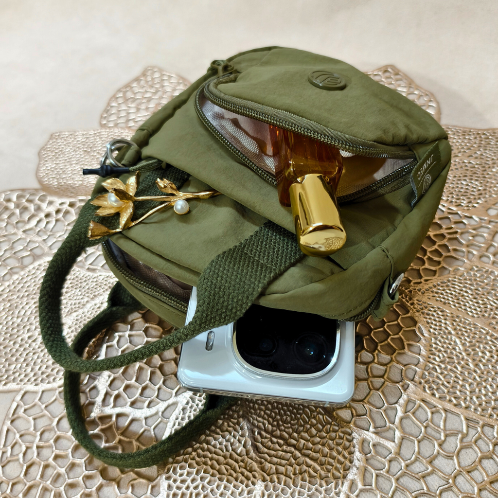 Green bag with gold jewelry on a textured surface