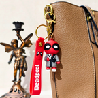 Deadpool keychain attached to a brown leather bag with a statue in the background