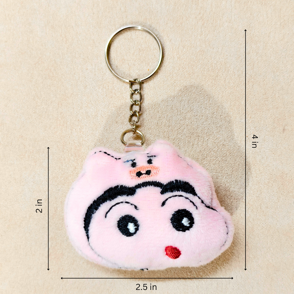 A plush keychain shaped like a cartoon pig face, featuring embroidered black eyebrows, eyes, and mouth details, a small red stitched nose, and a gold metal key ring and chain shown hand carry On Beige Background With Measurements.