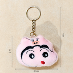 A plush keychain shaped like a cartoon pig face, featuring embroidered black eyebrows, eyes, and mouth details, a small red stitched nose, and a gold metal key ring and chain shown hand carry On Beige Background With Measurements.