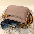 Brown textured handbag with sunglasses on a textured surface