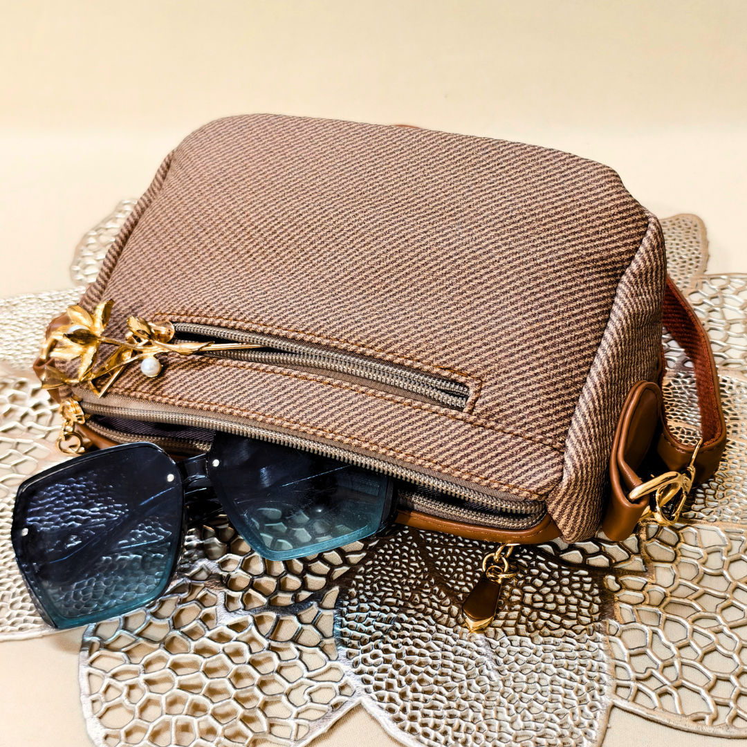Brown textured handbag with sunglasses on a textured surface